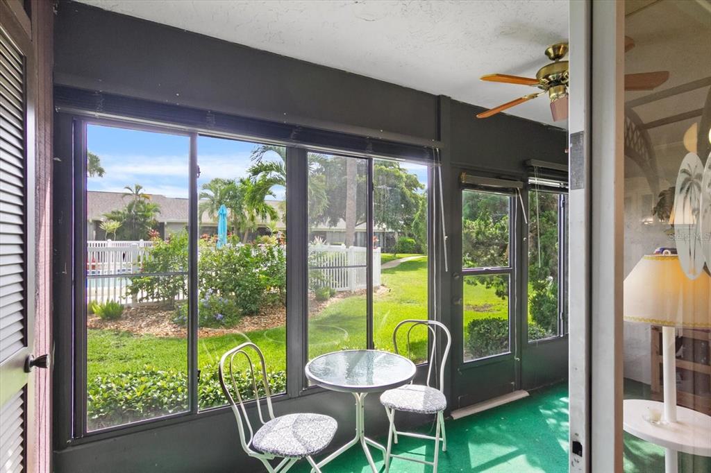 A sunroom with dark walls, green carpet, a ceiling fan, and a view of outdoors — 6108 7TH AVENUE W UNIT 6108, BRADENTON, FL