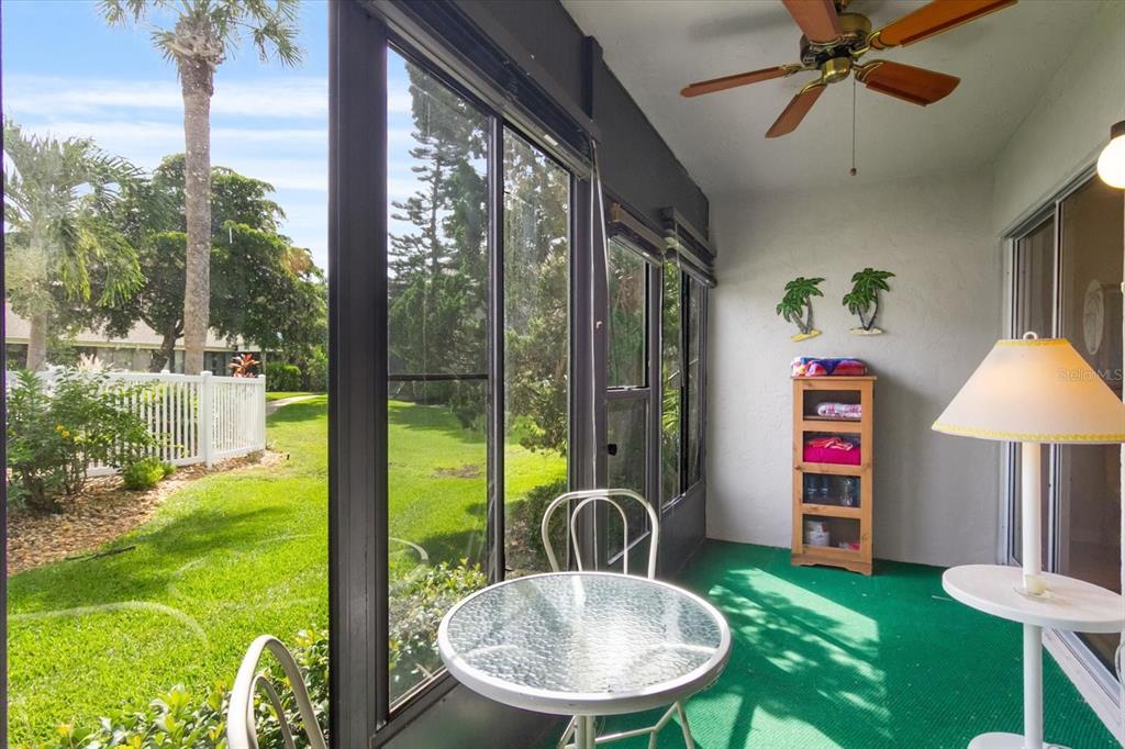 A screened-in porch with green carpeting, a glass-top table, and a view of the yard — 6108 7TH AVENUE W UNIT 6108, BRADENTON, FL