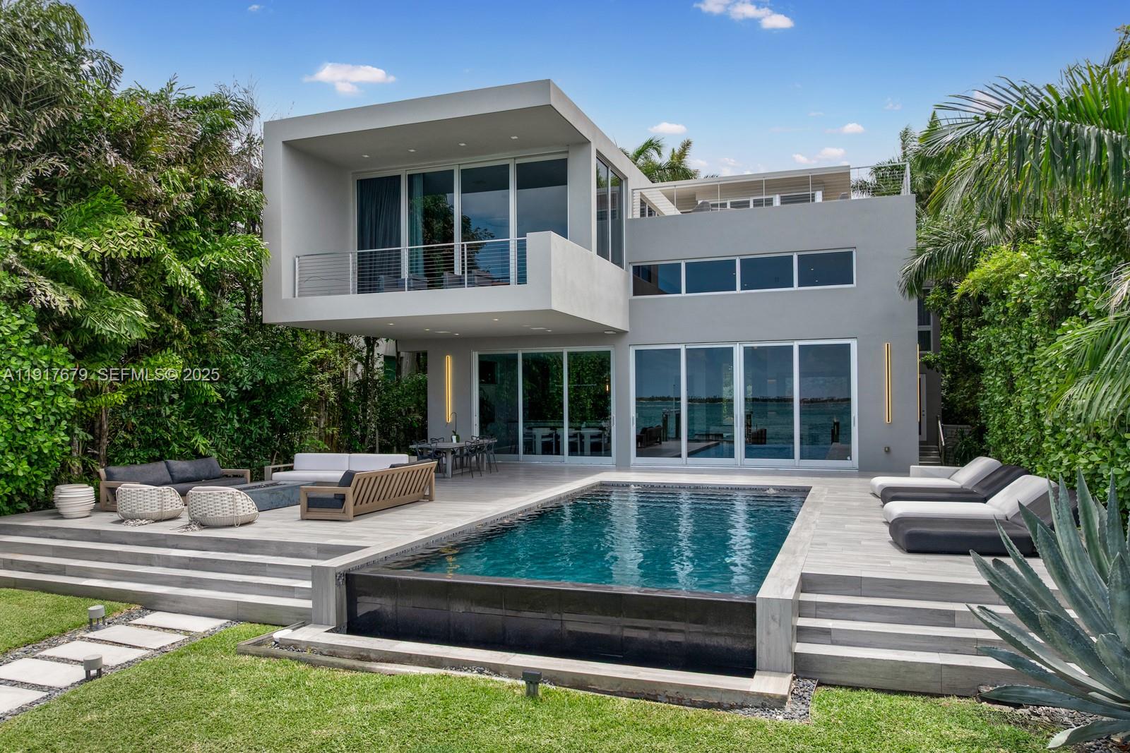 A modern two-story house features a swimming pool, patio furniture, and lush landscaping — 1379 N Venetian Way, Miami FL 33139, MIAMI, FL