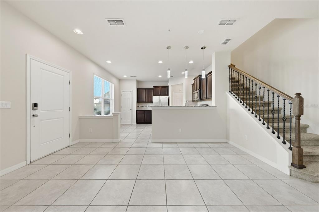 An open-concept interior features a tiled floor, a kitchen with dark cabinets, and a staircase — 1096 PAVIA DRIVE, APOPKA, FL