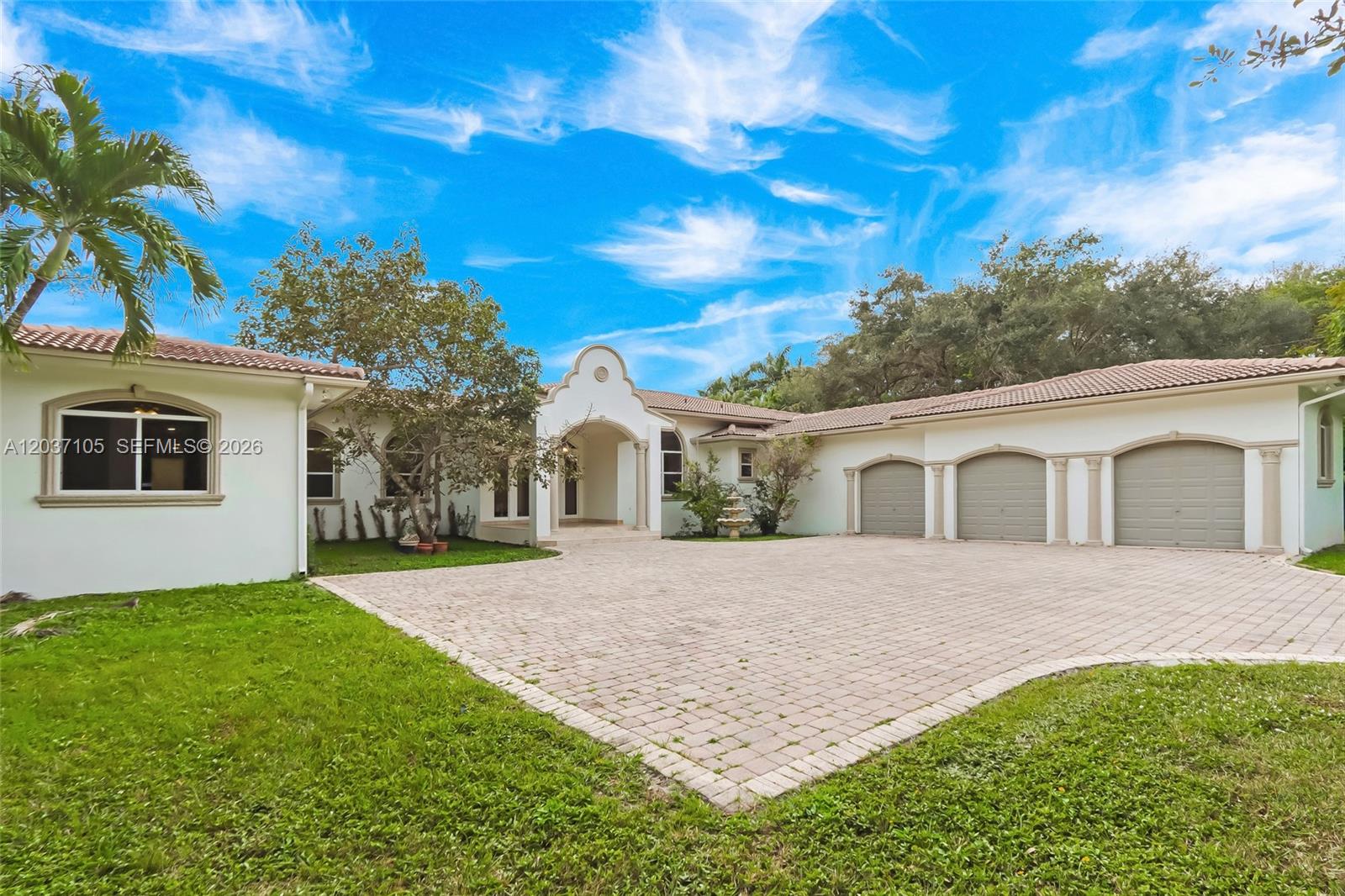 A single-story house with a paved driveway, three garage doors, and a central arched entryway — 8480 SW 98th St, Miami FL 33156, MIAMI, FL