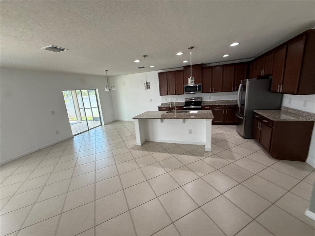 A kitchen with dark wood cabinets, granite countertops, a center island, and tile flooring — 11301 HUDSON HILLS LANE, RIVERVIEW, FL