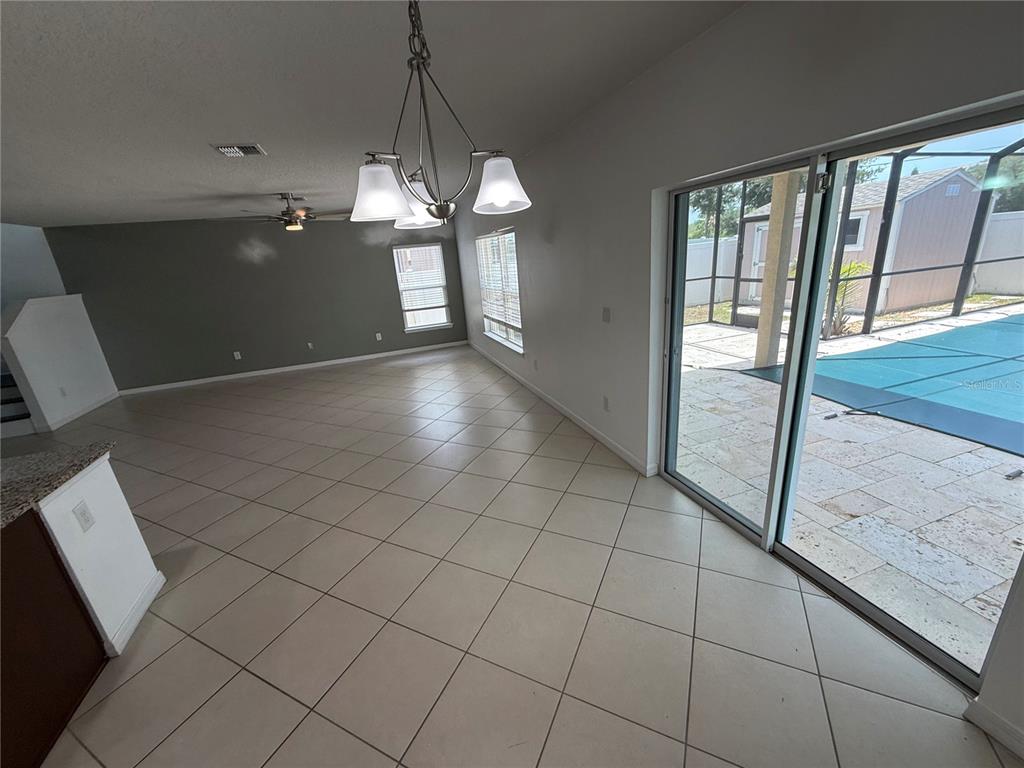 A dining area with tile floors, a chandelier, and sliding doors opening to a pool — 11301 HUDSON HILLS LANE, RIVERVIEW, FL