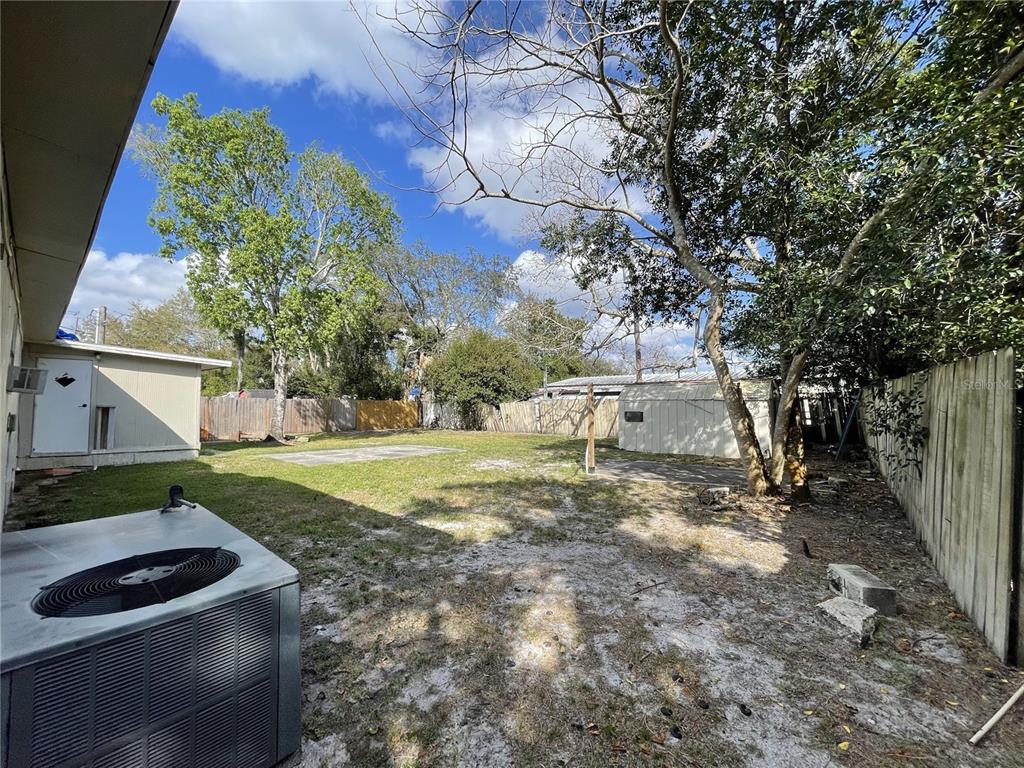 A fenced backyard features a grassy lawn, a concrete patio, a shed, and an air conditioner — 4503 USHER AVENUE, ORLANDO, FL