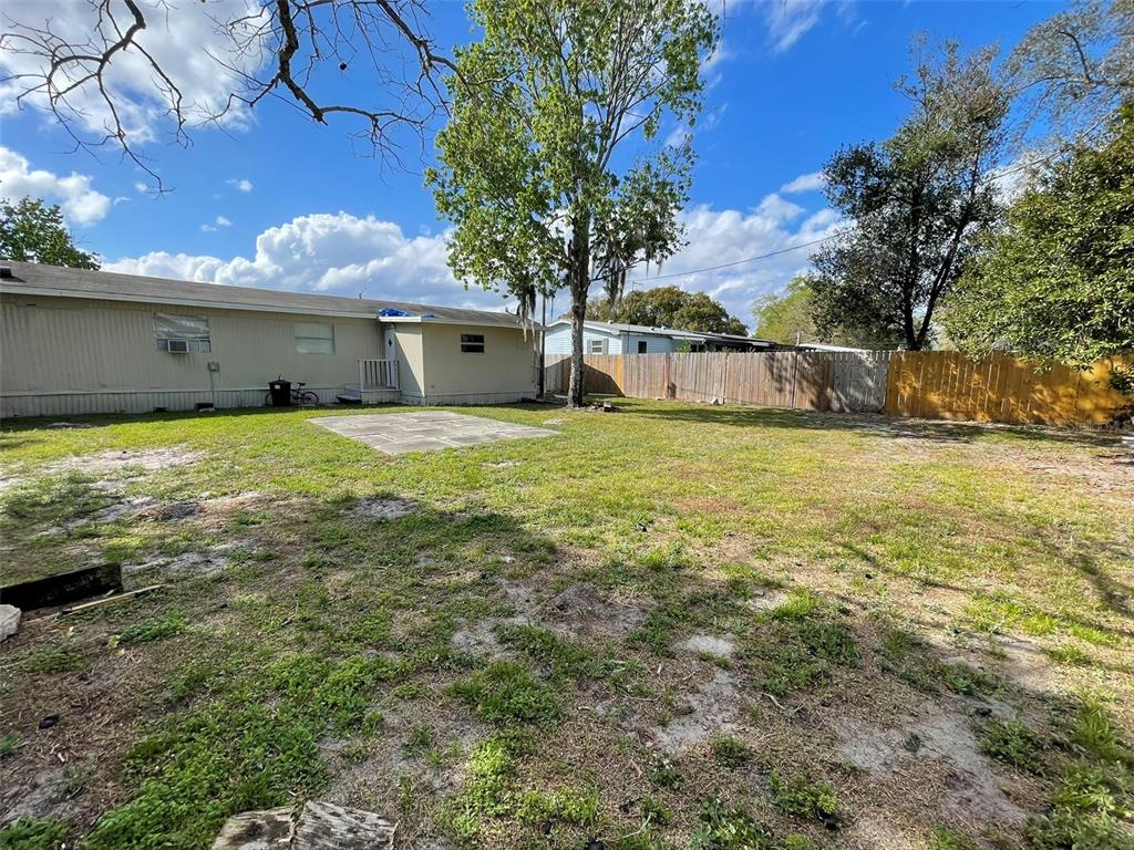A backyard features a concrete patio, a mobile home, and a wooden privacy fence — 4503 USHER AVENUE, ORLANDO, FL