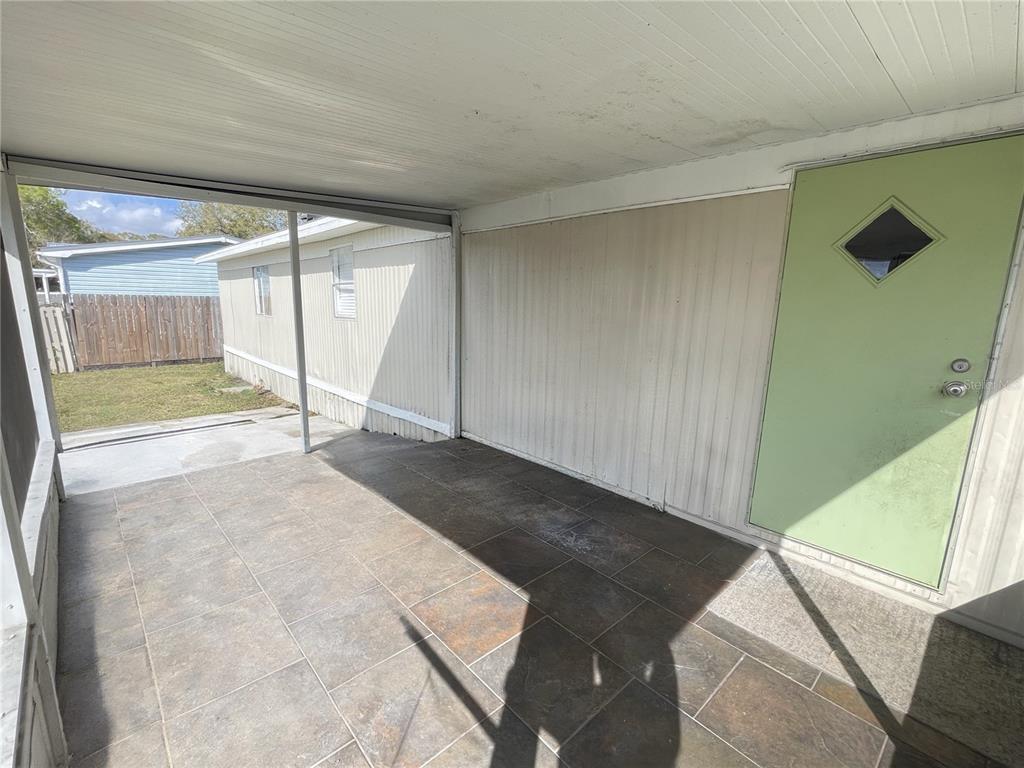 A covered patio with tiled flooring leads to a light green door — 4503 USHER AVENUE, ORLANDO, FL