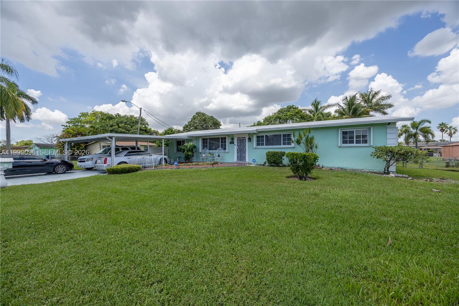 A light green single-story house features a carport, a large lawn, and palm trees — 11298 NW 21st Ct, Miami FL 33167, MIAMI, FL