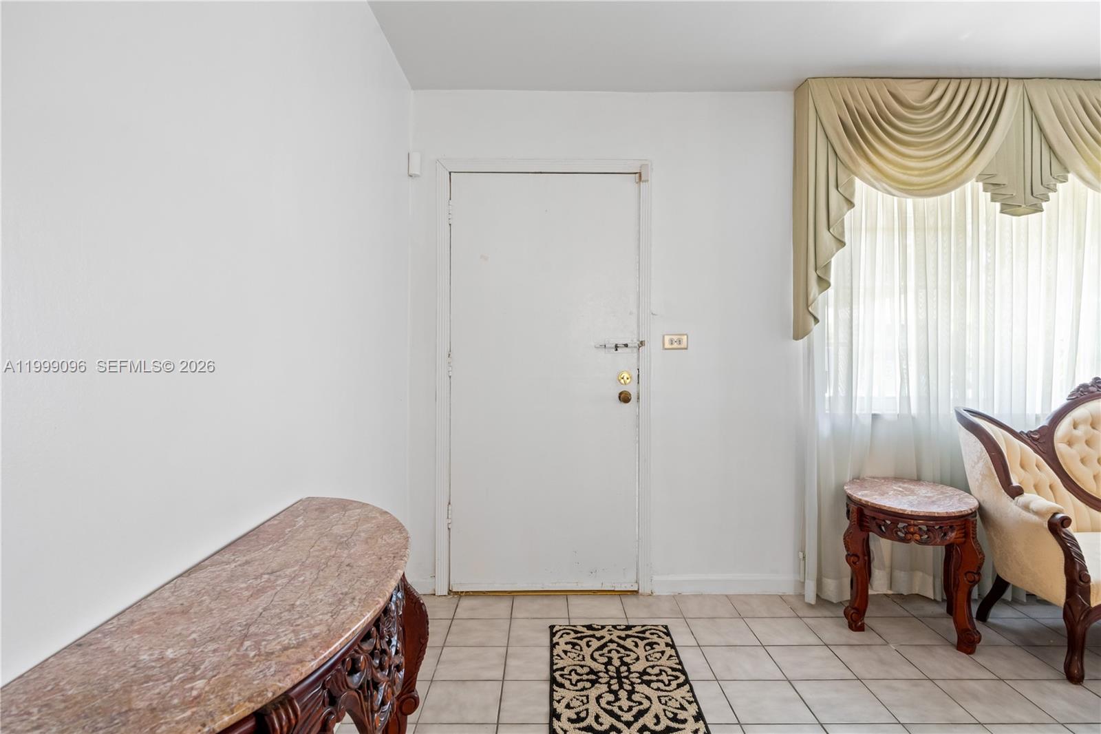 An entryway features a white door, tiled flooring, a marble-topped console table, and ornate furniture — 11298 NW 21st Ct, Miami FL 33167, MIAMI, FL
