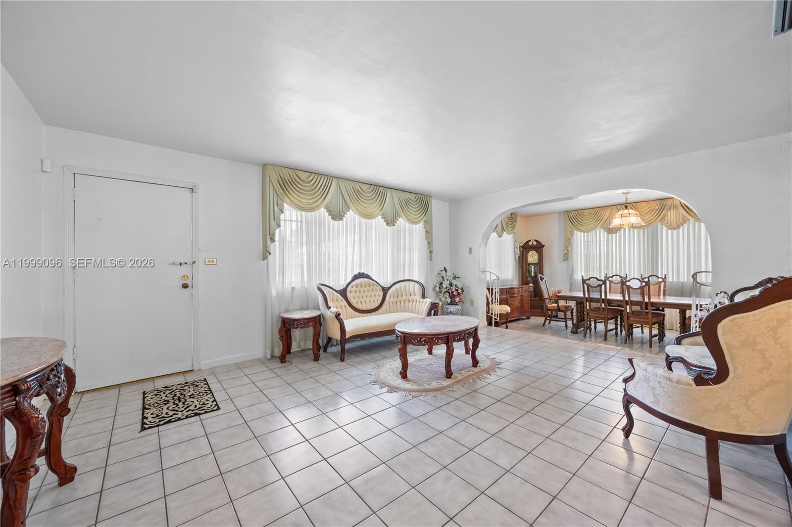 A living and dining room area features white tile floors, arched openings, and traditional furniture — 11298 NW 21st Ct, Miami FL 33167, MIAMI, FL