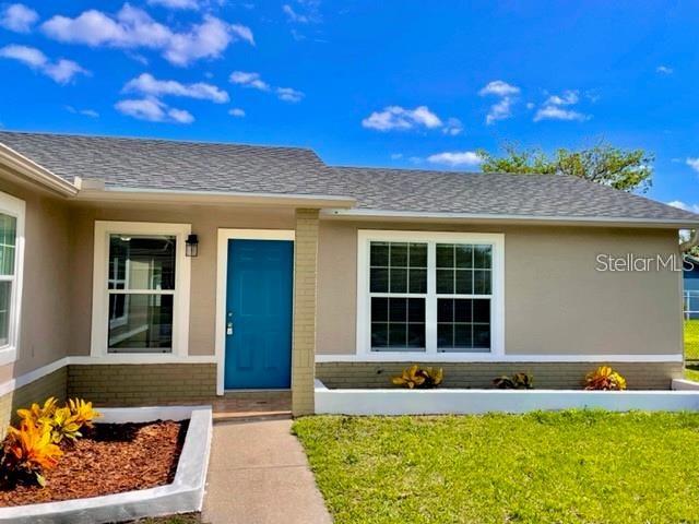 The exterior of a single-story house features a blue front door and tan siding — 705 HARLAND COURT, KISSIMMEE, FL