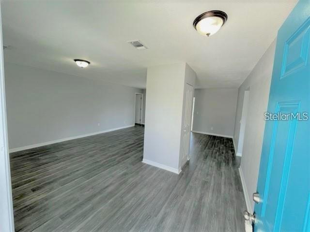 An interior view of a room with gray wood-look flooring and a bright blue door — 705 HARLAND COURT, KISSIMMEE, FL
