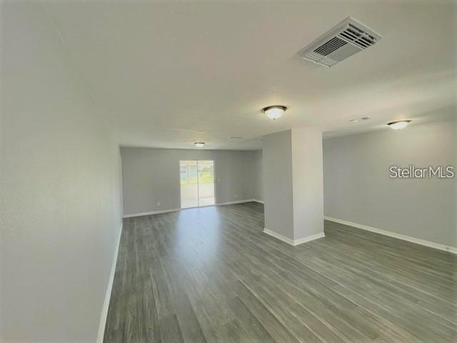 An open-concept living area features light gray walls, wood-look flooring, and a sliding glass door — 705 HARLAND COURT, KISSIMMEE, FL