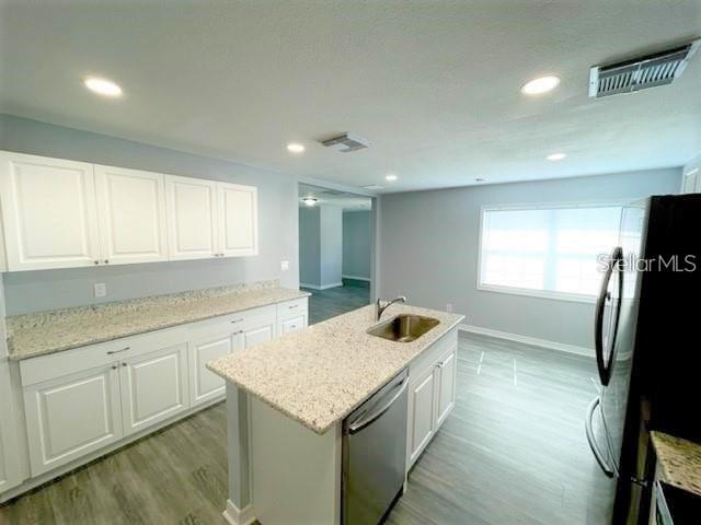A kitchen with white cabinets, granite countertops, a center island, and light-colored wood-look flooring — 705 HARLAND COURT, KISSIMMEE, FL
