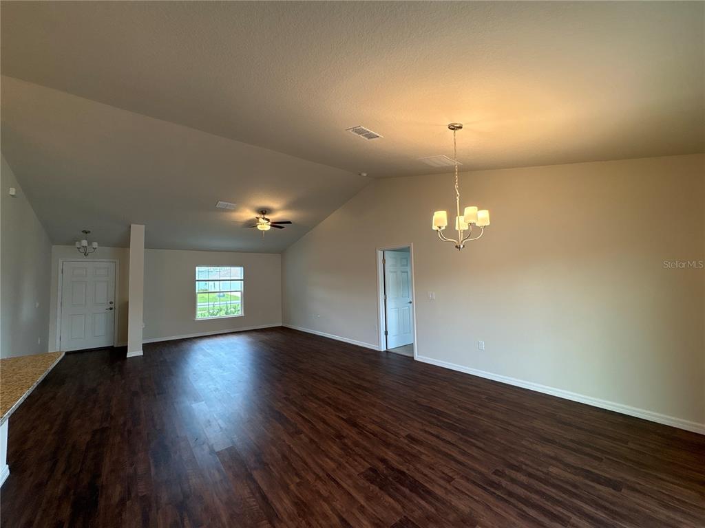 A spacious living area features vaulted ceilings, dark wood-look flooring, and a chandelier — 3491 SW 155TH LANE, OCALA, FL