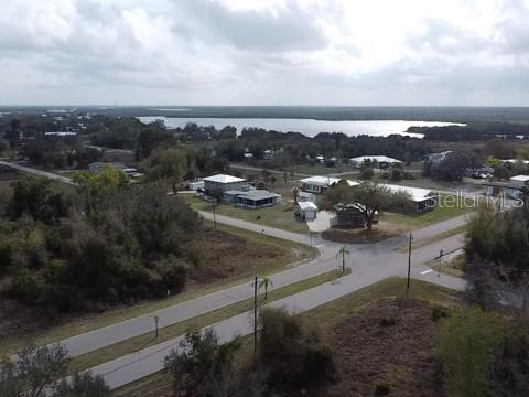 An aerial view shows a residential neighborhood with houses near a large lake — 29181 DEFIANCE AVENUE, PUNTA GORDA, FL