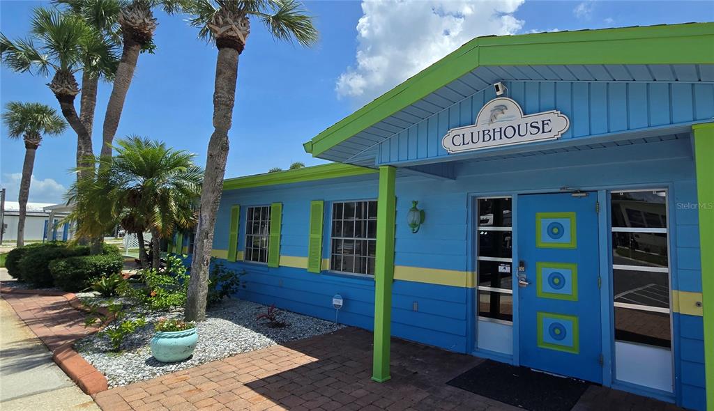 A blue and lime green clubhouse building features a brick walkway and palm trees — 9 YAWL LANE UNIT 9, PALM HARBOR, FL