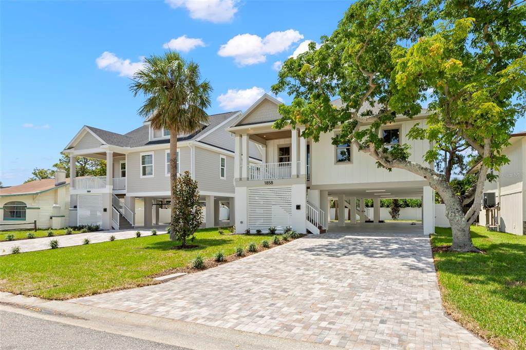 Two elevated coastal-style houses with paved driveways and green lawns under a blue sky — 1858 MISSISSIPPI AVENUE NE, ST PETERSBURG, FL