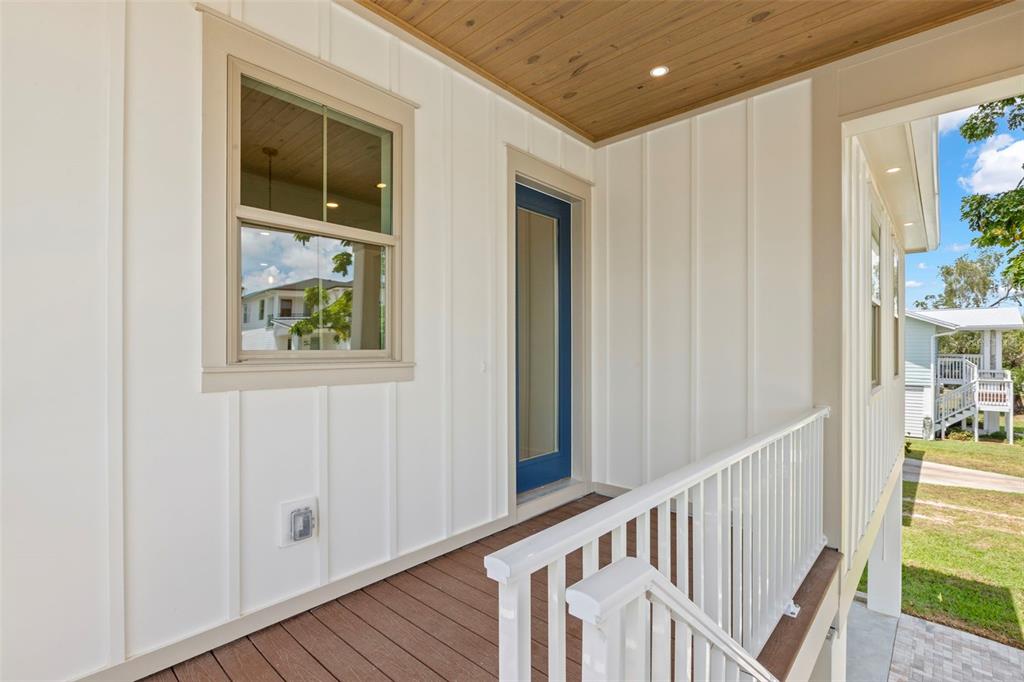 A covered porch features white board-and-batten siding, a blue door, and a wooden ceiling — 1858 MISSISSIPPI AVENUE NE, ST PETERSBURG, FL