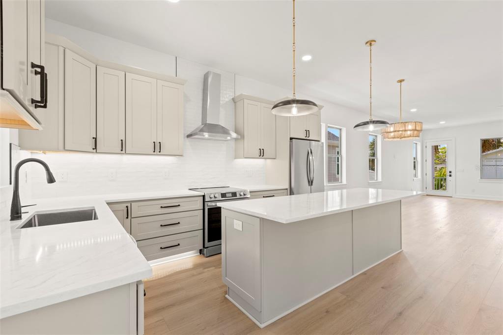 A modern kitchen features light gray cabinetry, white quartz countertops, stainless steel appliances, and wood flooring — 1858 MISSISSIPPI AVENUE NE, ST PETERSBURG, FL