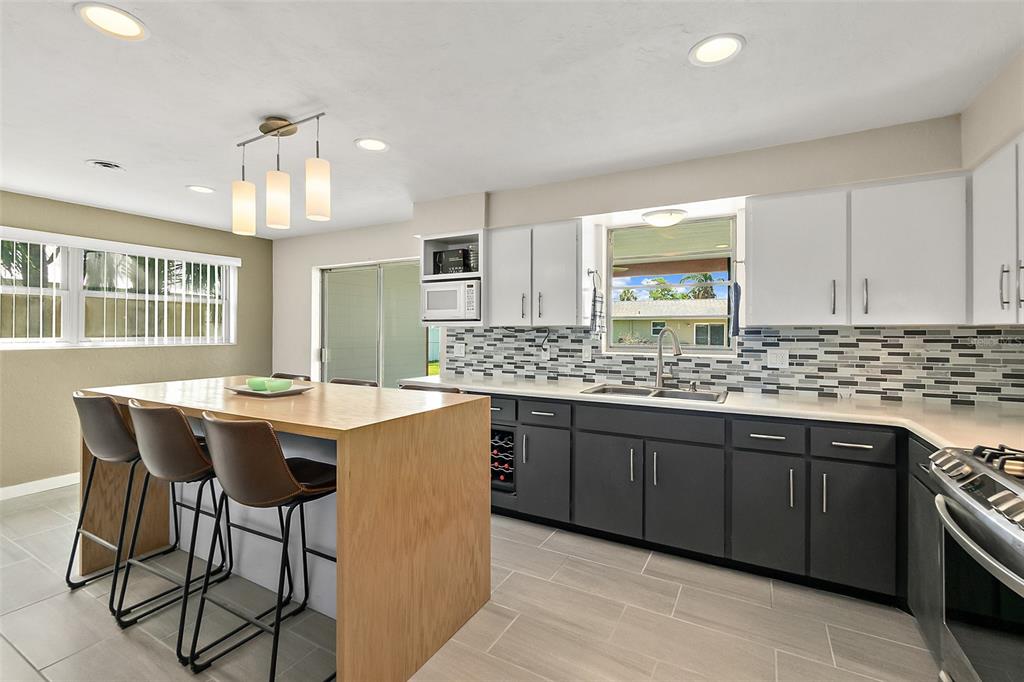 A kitchen features a wooden island with bar stools, dark lower cabinets, and white upper cabinets — 1662 LOUISIANA ROAD, SOUTH DAYTONA, FL