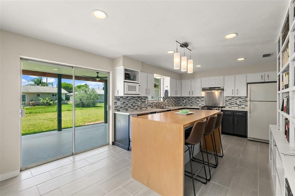 A kitchen with a wooden island, white upper cabinets, dark lower cabinets, and sliding glass doors — 1662 LOUISIANA ROAD, SOUTH DAYTONA, FL