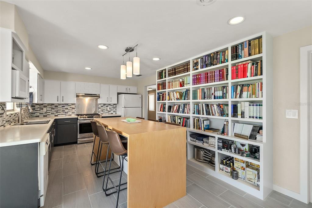 A kitchen with a large wooden island, white cabinets, and a floor-to-ceiling built-in bookshelf — 1662 LOUISIANA ROAD, SOUTH DAYTONA, FL