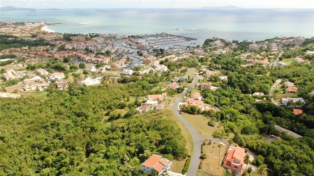 An aerial view shows a coastal town with a marina, surrounding hills, and residential houses — PORT ROAD ROAD UNIT 17, HUMACAO, PR