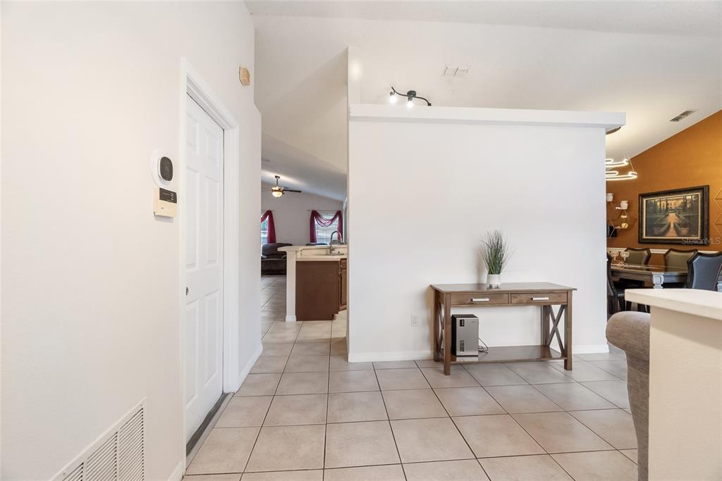 A tiled entryway leads to a kitchen and dining area with a wooden console table — 1219 MAYBROOK STREET S, APOPKA, FL