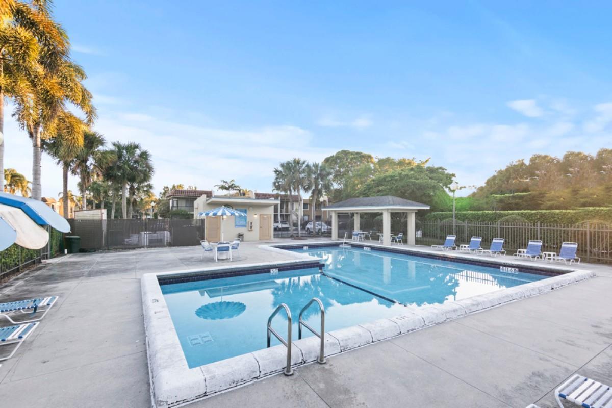 A rectangular swimming pool with a surrounding patio, lounge chairs, and a small pavilion — 428 Lakeview Drive # 201, Weston FL 33326, WESTON, FL