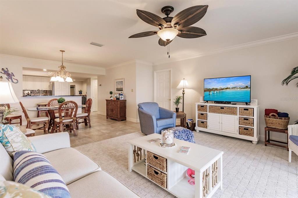 A living room with a ceiling fan, white furniture, and an adjacent dining area — 1125 W PEPPERTREE DRIVE UNIT 605, SARASOTA, FL