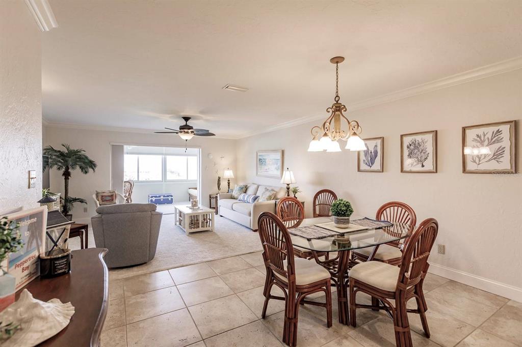 A dining area with a glass table and rattan chairs opens into a living room — 1125 W PEPPERTREE DRIVE UNIT 605, SARASOTA, FL