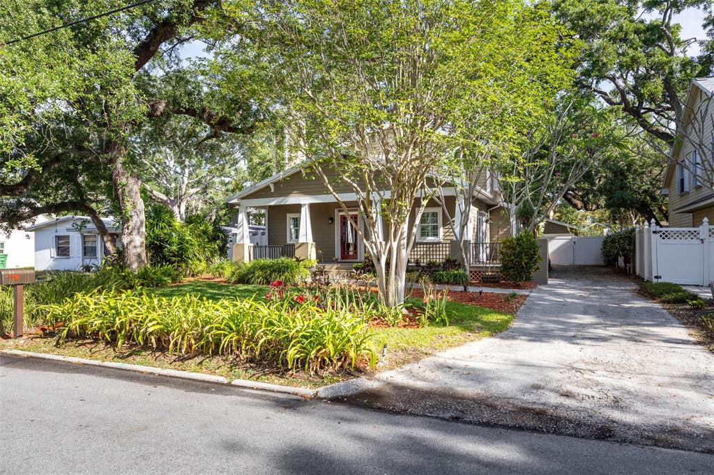 A tan house with a front porch and a concrete driveway sits behind a grassy yard — 3311 W HAWTHORNE ROAD, TAMPA, FL