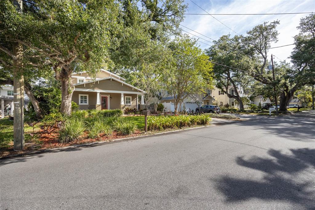 A tan two-story house with a front porch sits on a tree-lined residential street — 3311 W HAWTHORNE ROAD, TAMPA, FL