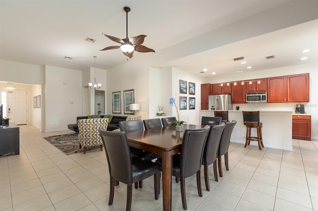 An open-concept dining area and kitchen with tile floors, dark wood furniture, and cabinetry — 7739 TEASCONE BOULEVARD, KISSIMMEE, FL