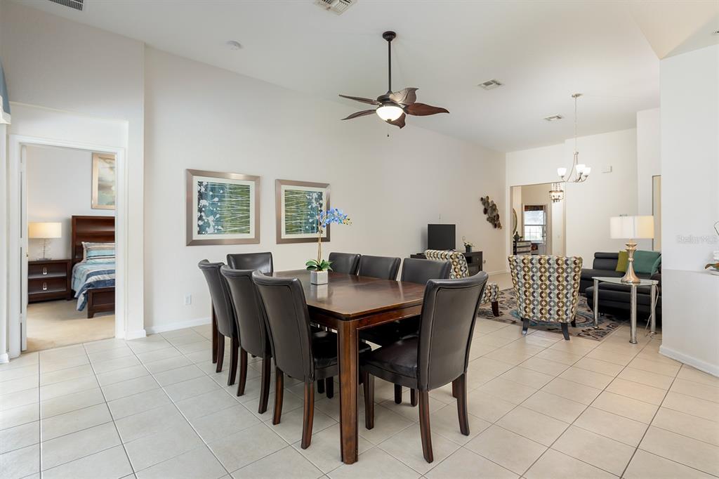 A dining room with a dark wood table and chairs sits adjacent to a living area — 7739 TEASCONE BOULEVARD, KISSIMMEE, FL