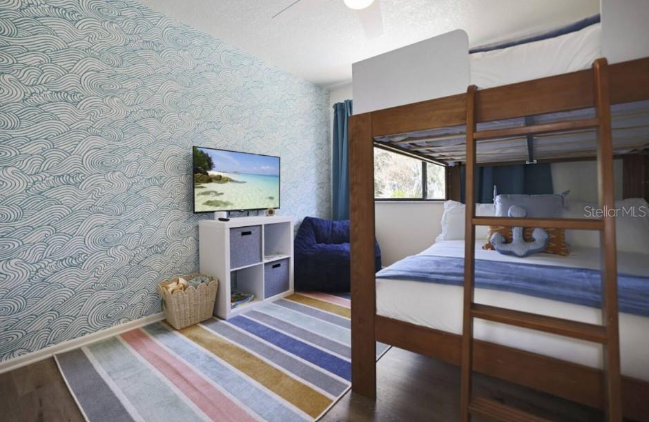 A bedroom features a bunk bed, patterned wallpaper, a television, and a striped area rug — 10075 W BAY STREET, SEMINOLE, FL