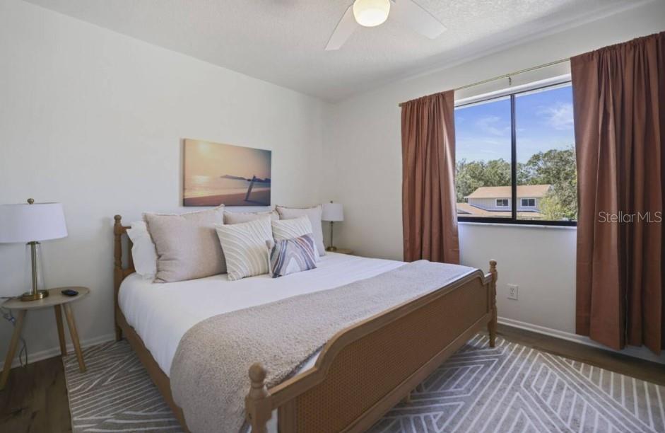 A bedroom features a wooden bed frame, a patterned rug, and brown curtains by a window — 10075 W BAY STREET, SEMINOLE, FL
