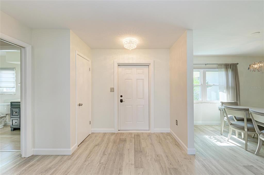 An entryway features light wood-look flooring, a white front door, and a nearby dining area — 3368 SHEFFIELD CIRCLE, SARASOTA, FL