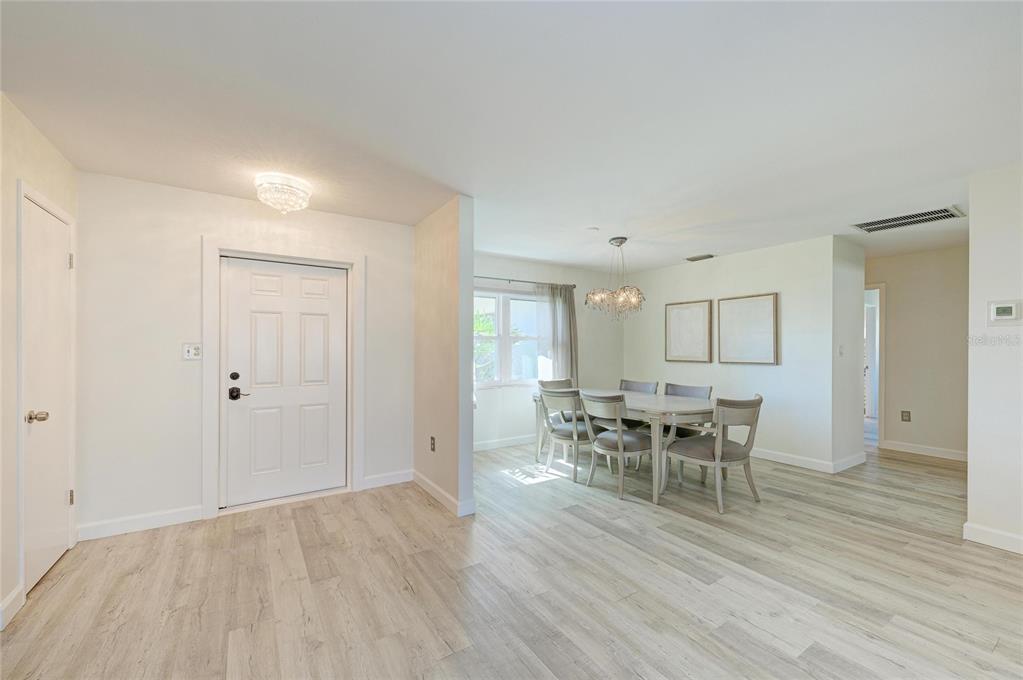 A bright dining area features light wood-look flooring, a white front door, and a chandelier — 3368 SHEFFIELD CIRCLE, SARASOTA, FL