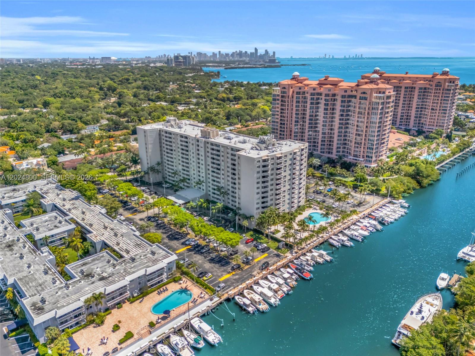 An aerial view shows waterfront apartment buildings with a marina, swimming pools, and parking lots — 90 Edgewater Dr # 1201, Coral Gables FL 33133, CORAL GABLES, FL