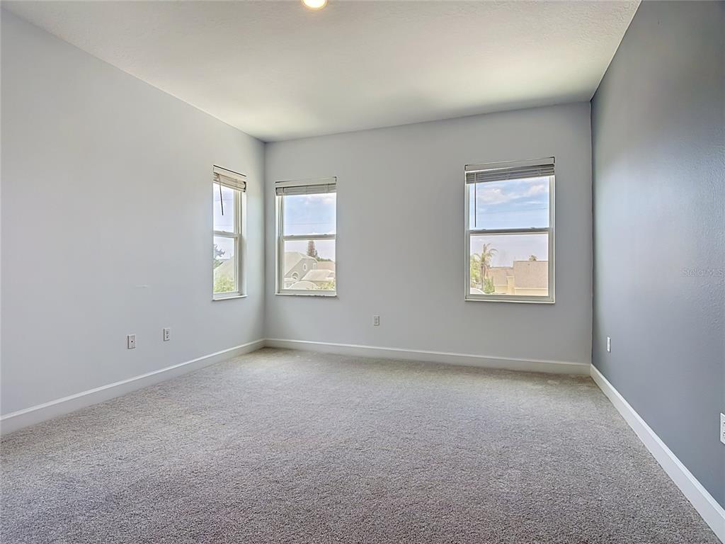 An empty bedroom features light gray walls, a dark accent wall, and beige carpeting — 148 BOYDFIELD LANE, DAVENPORT, FL