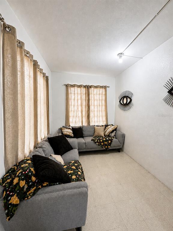 A living room features two gray sofas, beige curtains, and a decorative eye wall hanging — Carretera 132 BO. TALLABOA ALTA, PENUELAS, PR