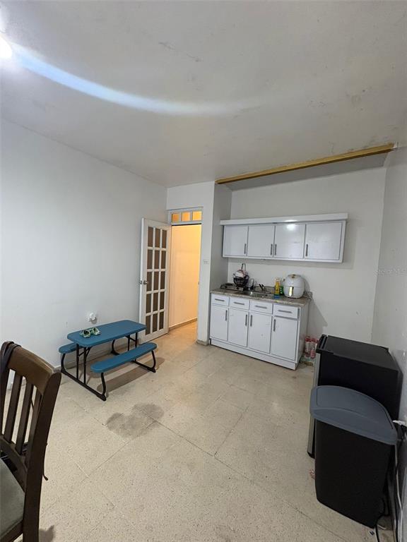 A small kitchen area features white cabinets, a blue picnic-style table, and tile flooring — Carretera 132 BO. TALLABOA ALTA, PENUELAS, PR