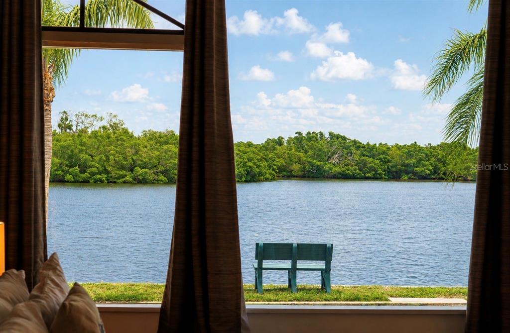 A view of a lake and a green bench through a large window with curtains — 611 DESTINY DRIVE UNIT 307, RUSKIN, FL