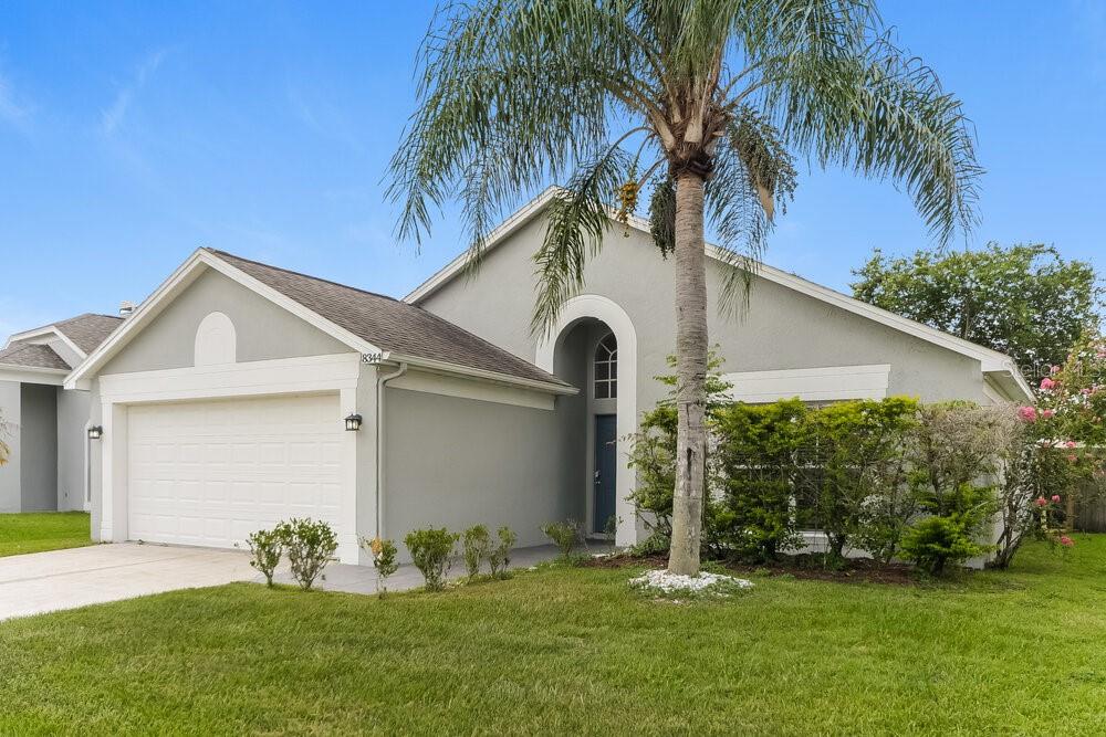 A single-story house with a two-car garage, a palm tree, and a covered entryway — 8344 FORT THOMAS WAY, ORLANDO, FL
