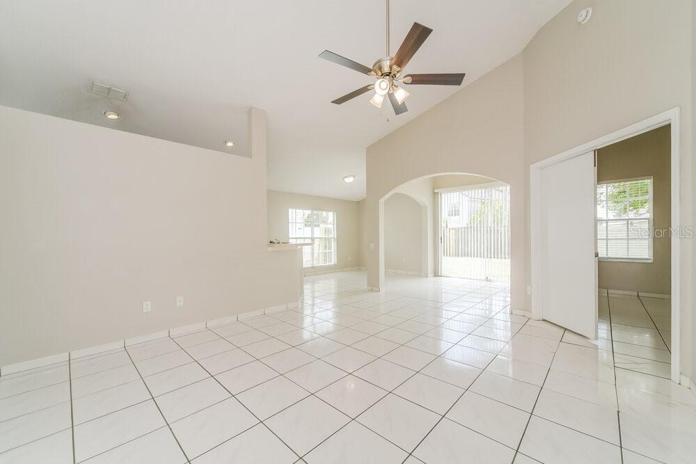 An open-concept living area with white tile flooring, vaulted ceilings, and a ceiling fan — 8344 FORT THOMAS WAY, ORLANDO, FL