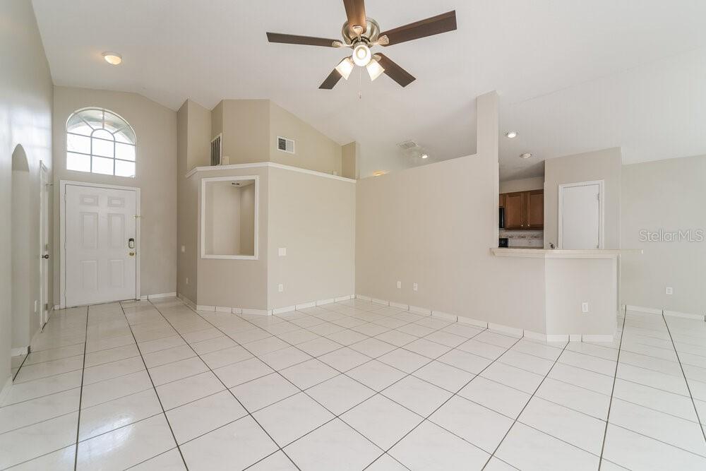 An open-concept living area features white tile flooring, vaulted ceilings, and an adjacent kitchen — 8344 FORT THOMAS WAY, ORLANDO, FL