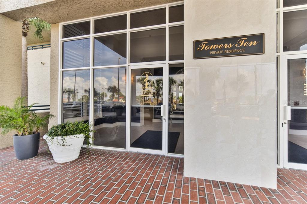 The exterior entrance of a building features a glass door, brick flooring, and potted plants — 3425 S ATLANTIC AVENUE UNIT 1102, DAYTONA BEACH, FL