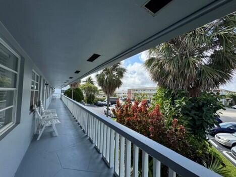 An outdoor balcony with white railings overlooks a parking lot and palm trees — 751 Pine Drive # 104, Pompano Beach FL 33060, POMPANO BEACH, FL