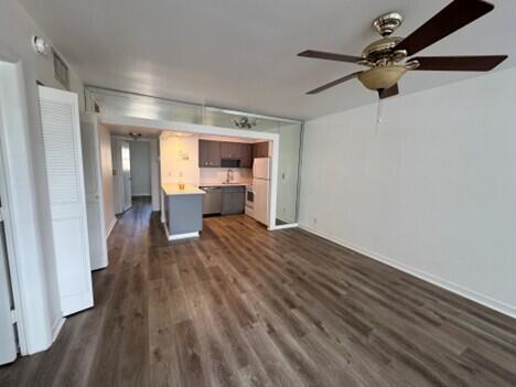 An open-concept living area features wood-look flooring, a ceiling fan, and a compact kitchen — 751 Pine Drive # 104, Pompano Beach FL 33060, POMPANO BEACH, FL